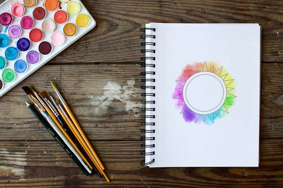 better-color-choices A drawing of a color wheel with various paints on a notebook.